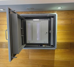 Firefighter using a Gerda Security evacuation alert panel during a high-rise emergency.